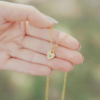 Woman holding her Cherished hearts initials necklace handcrafted in 14k yellow gold with personalized charm