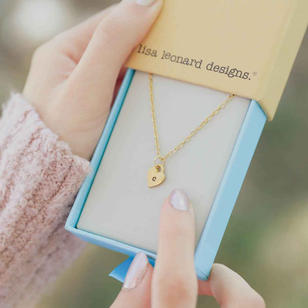 Woman holding her Cherished hearts initials necklace handcrafted in 14k yellow gold with personalized charm