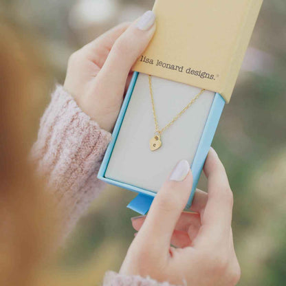 Woman holding her Cherished hearts initials necklace handcrafted in 10k yellow gold with personalized charm