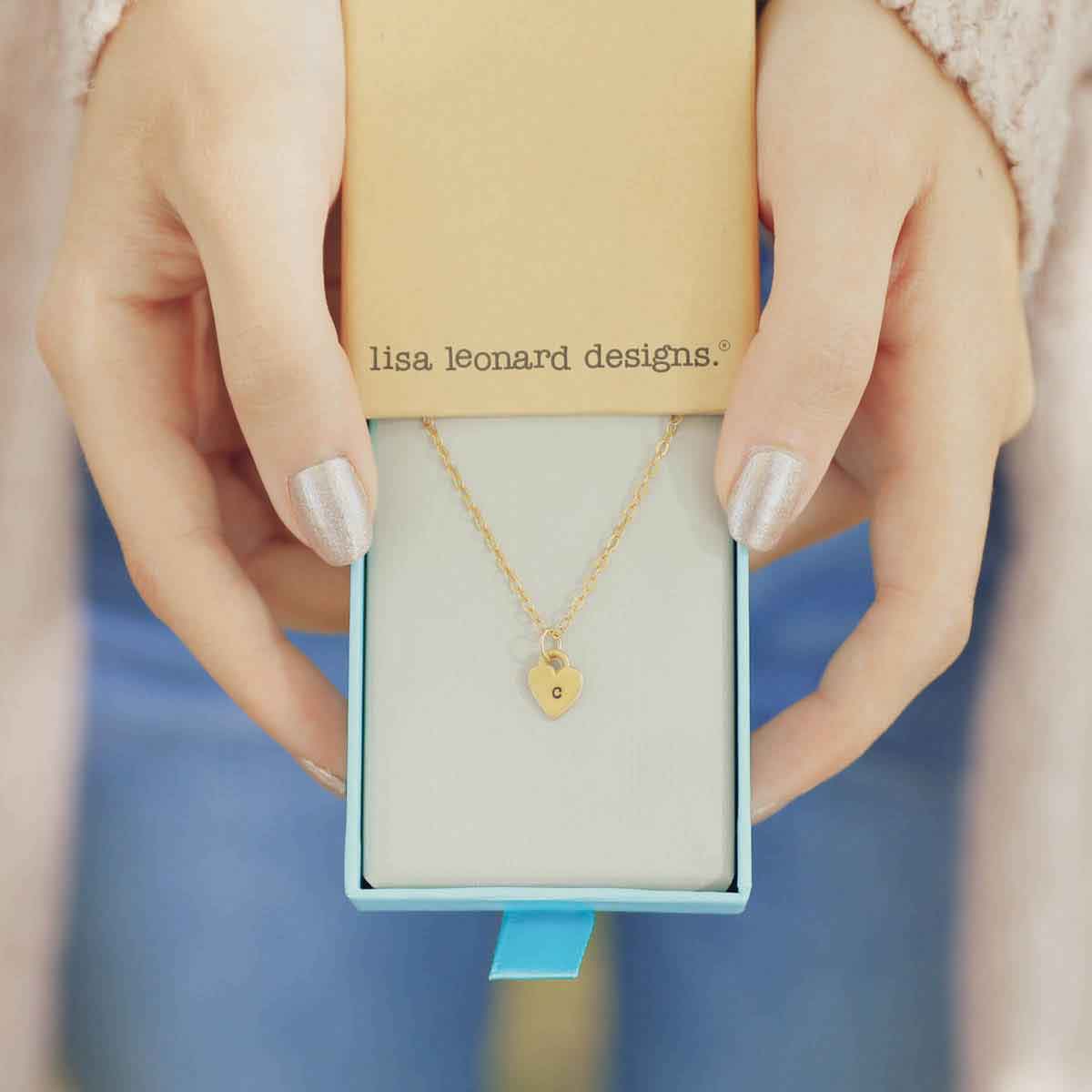 Woman holding her Cherished hearts initials necklace handcrafted in 14k yellow gold with personalized charm