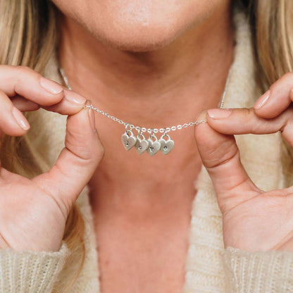 Girl wearing her Cherished hearts initials necklace handcrafted in sterling silver including two customizable sterling silver charms