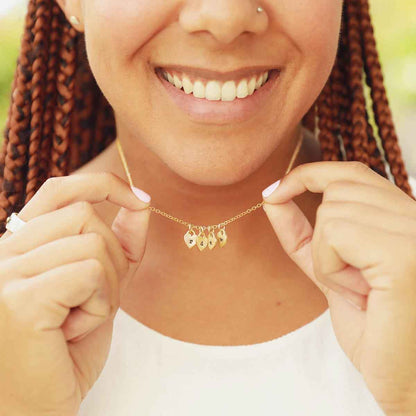 Woman wearing her Cherished hearts initials necklace handcrafted in 14k yellow gold including customizable charms