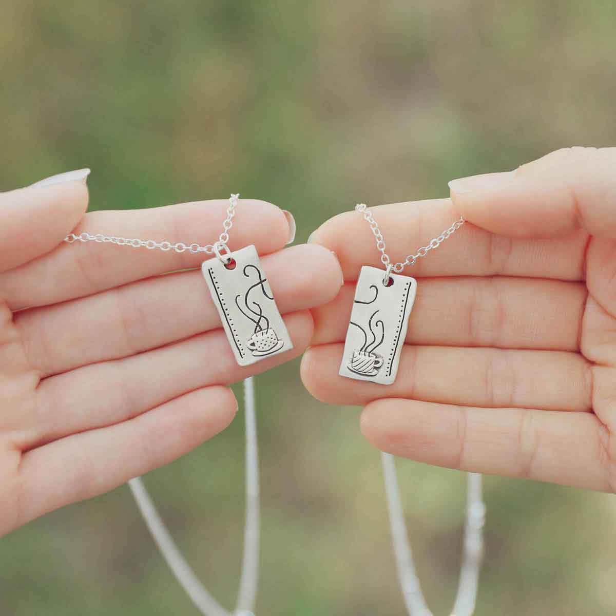 hands holding the Coffee and tea necklace set handcrafted in sterling silver