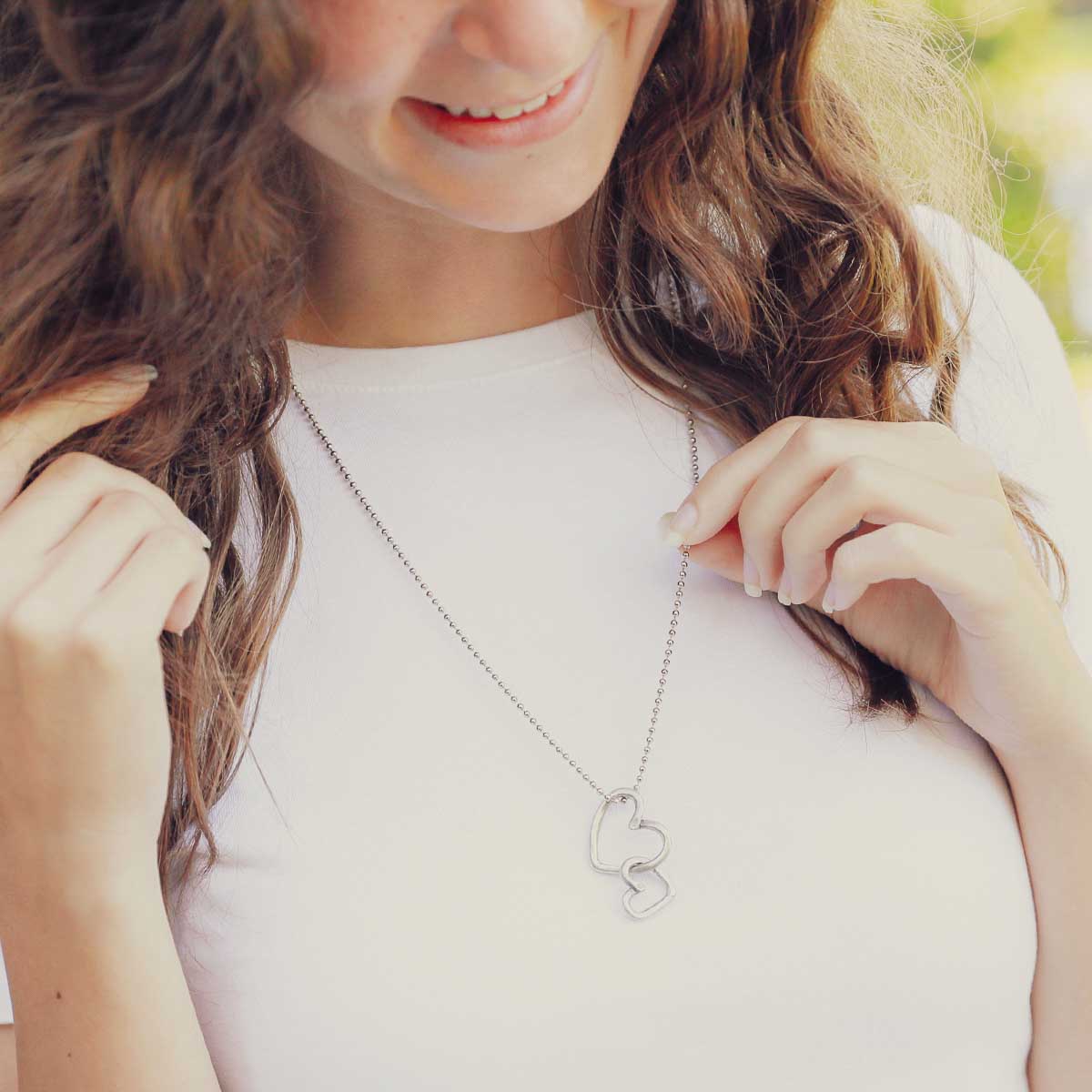 Girl wearing her Connected hearts necklace handcrafted in pewter including a pair of heart charms