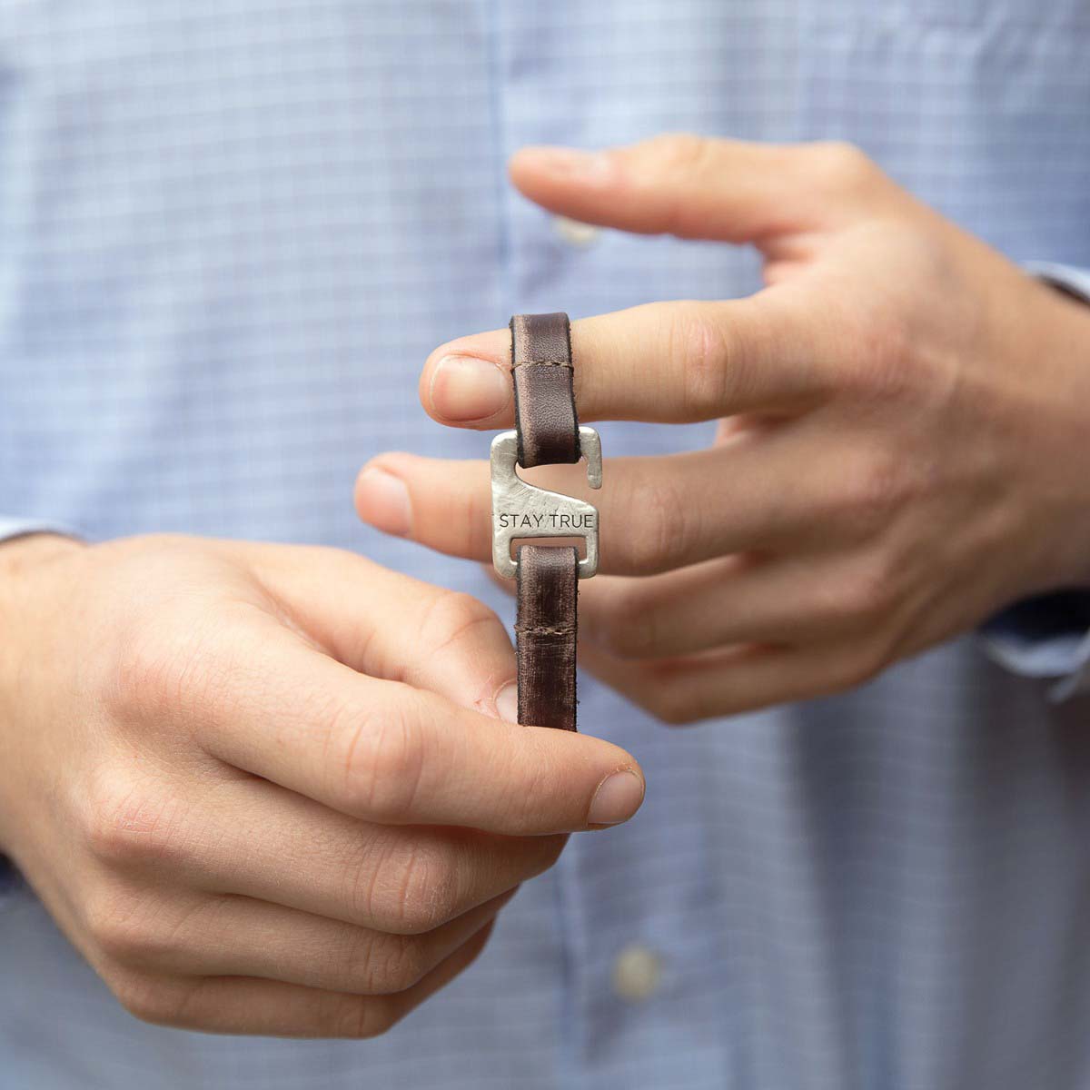 Man wearing Brown Connection bracelet handcrafted with a distressed leather strap and sterling silver closure customizable with a name