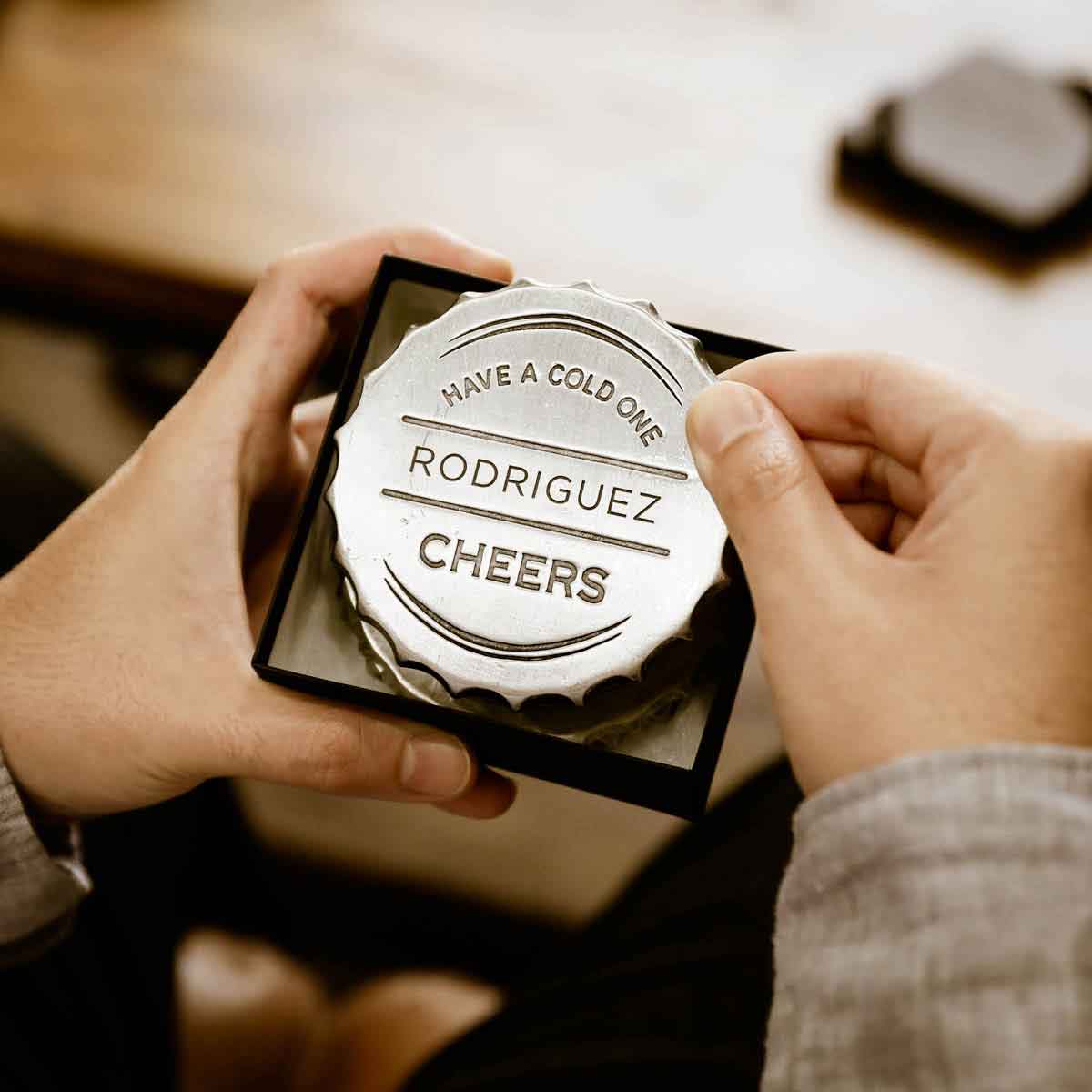 close up of the Crafting Memories Coaster on a wooden table with a hand holding a beer bottle 