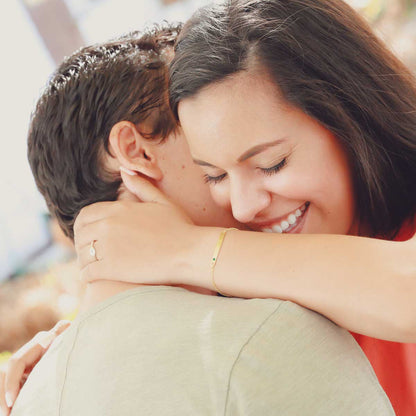 Couple hugging with woman wearing her personalized 14k cross bar birthstone bracelet