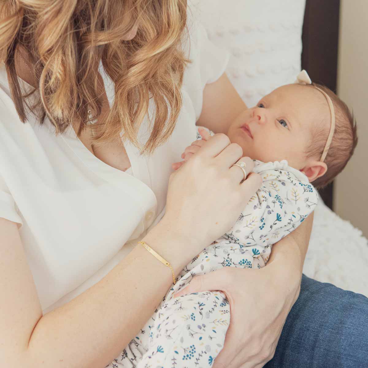 Woman holding her baby wearing her personalized 10k cross bar birthstone bracelet