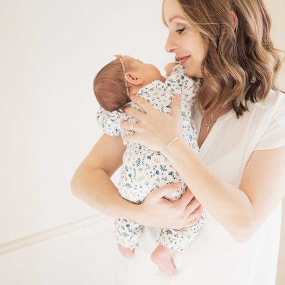 Woman holding her baby while wearing her personalized cross bar birthstone sterling silver bracelet