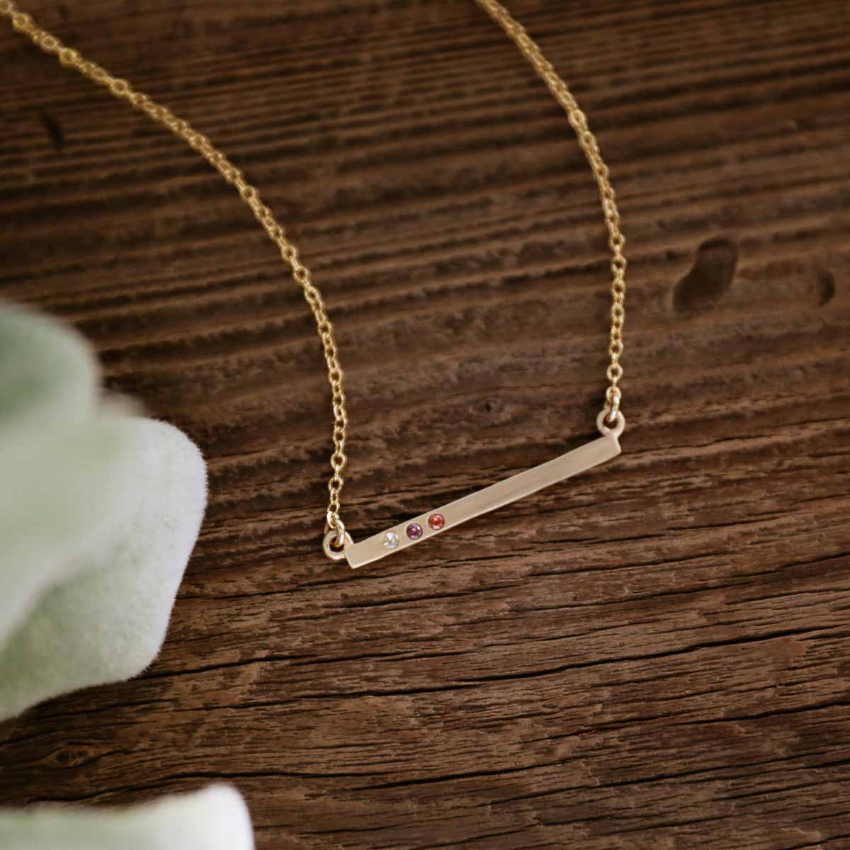 10k yellow gold cross bar birthstone necklace strung on a gold-filled link chain customizable with up to 7 genuine 2mm birthstones 