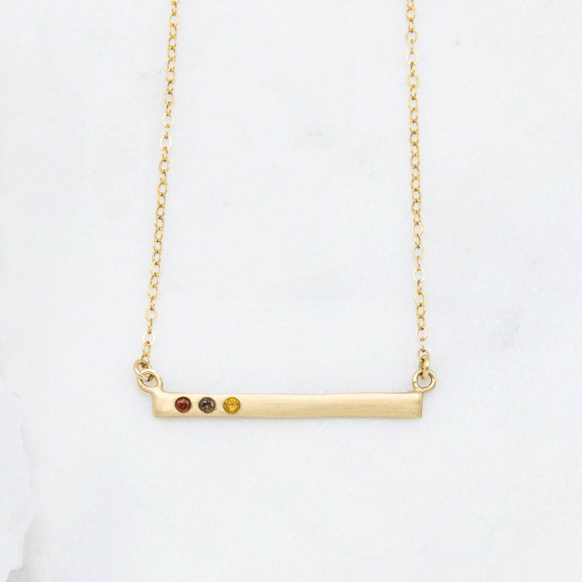 14k yellow gold cross bar birthstone necklace strung on a gold-filled link chain customizable with up to 7 genuine 2mm birthstones 