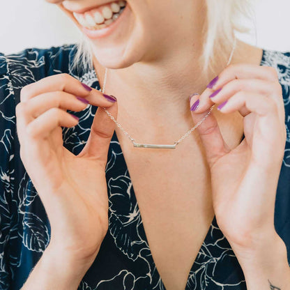 girl wearing sterling silver cross bar birthstone necklace strung on a silver link chain customizable with up to 7 genuine 2mm birthstones 