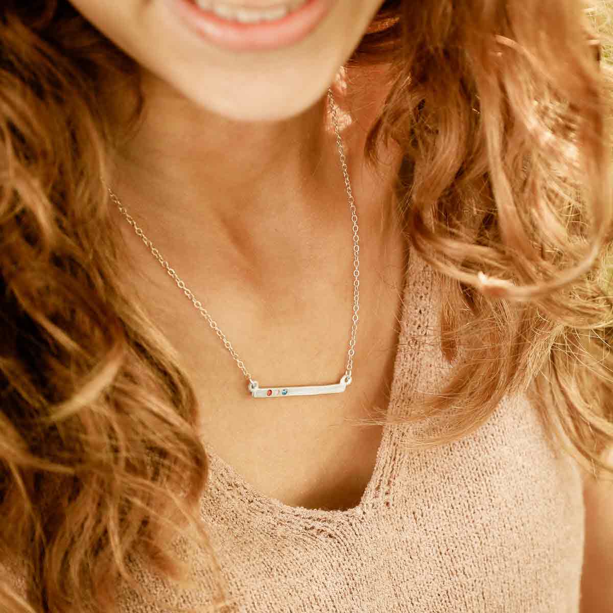 girl wearing sterling silver cross bar birthstone necklace strung on a link chain customizable with up to 7 genuine 2mm birthstones 