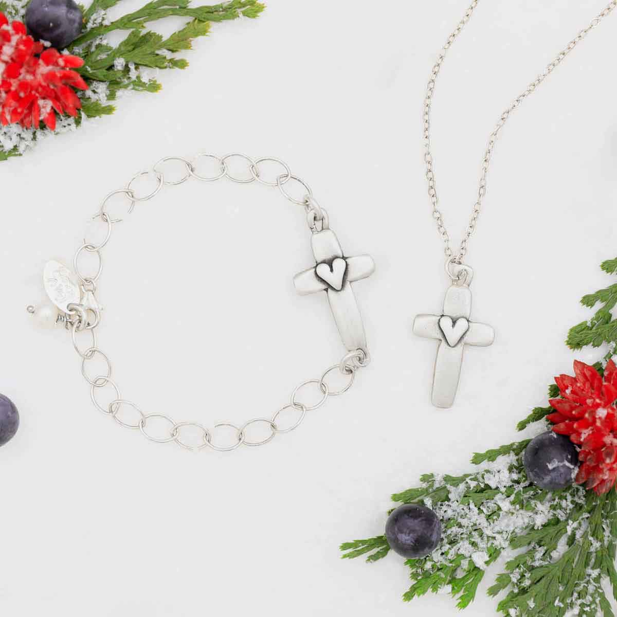 sterling silver cross of faith necklace and bracelet on white snow and some greenery