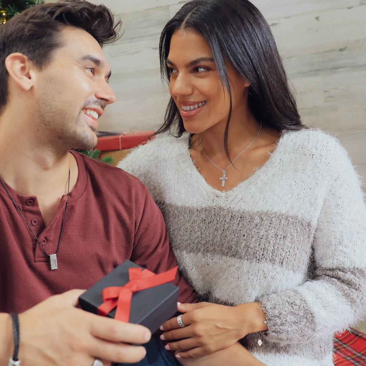 girl wearing sterling silver cross of faith necklace with guy gift exchanging in front of christmas tree