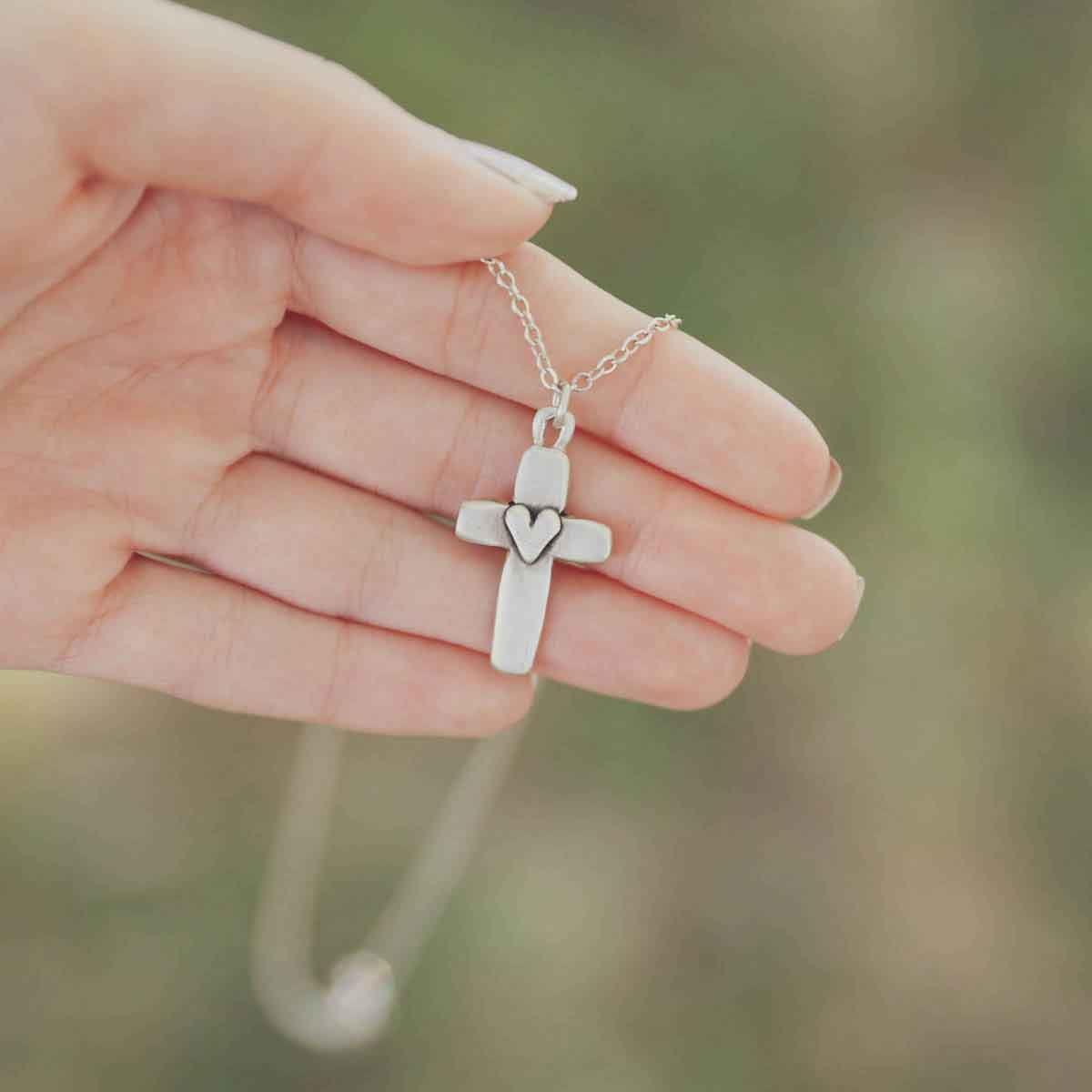 hand holding sterling silver cross of faith necklace