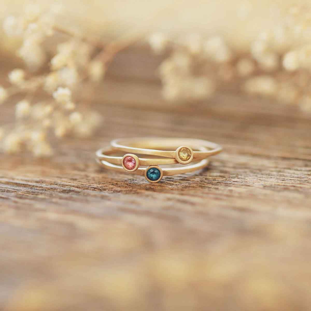 Handcrafted 10k yellow gold Dainty finespun birthstone rings stacked on wood