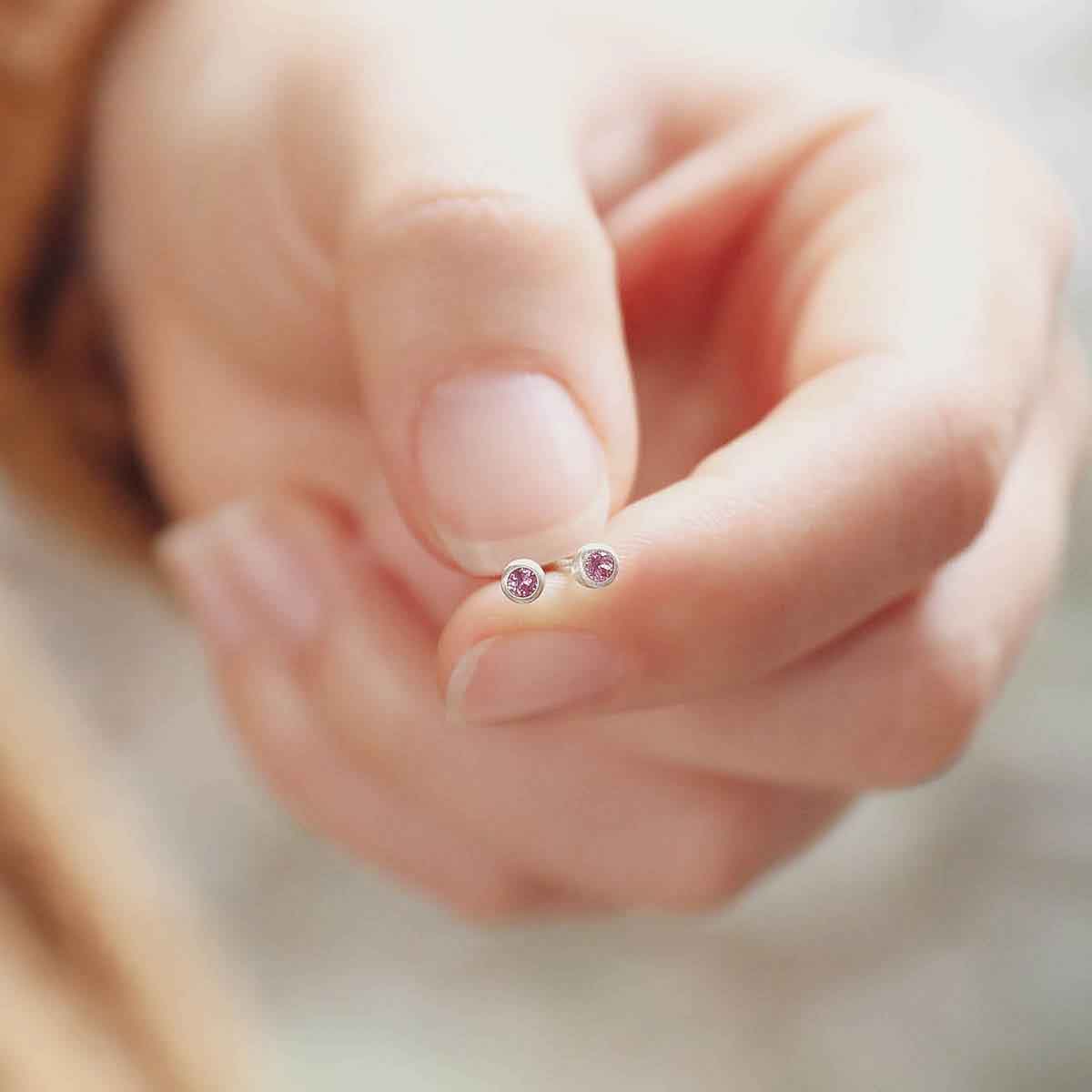 girl holding 2mm Dainty Finespun Birthstone Stud Earrings - Small in sterling silver