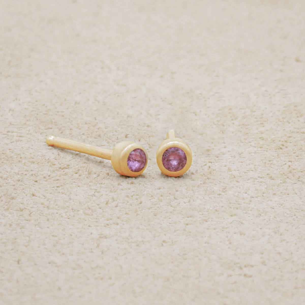 10K yellow gold Dainty Finespun Birthstone Stud Earrings - Small 2mm on a beige background