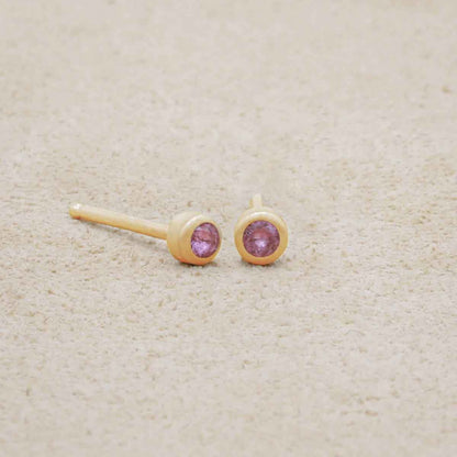 10K yellow gold Dainty Finespun Birthstone Stud Earrings - Small 2mm on a beige background