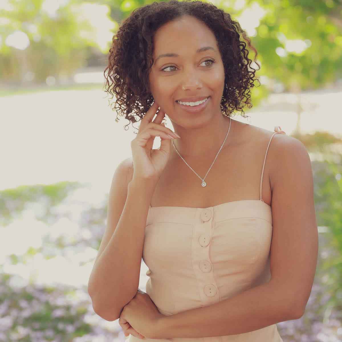 girl holding a Dainty Sunburst Necklace cast in Sterling Silver and set with a 3mm cubic zirconia stone