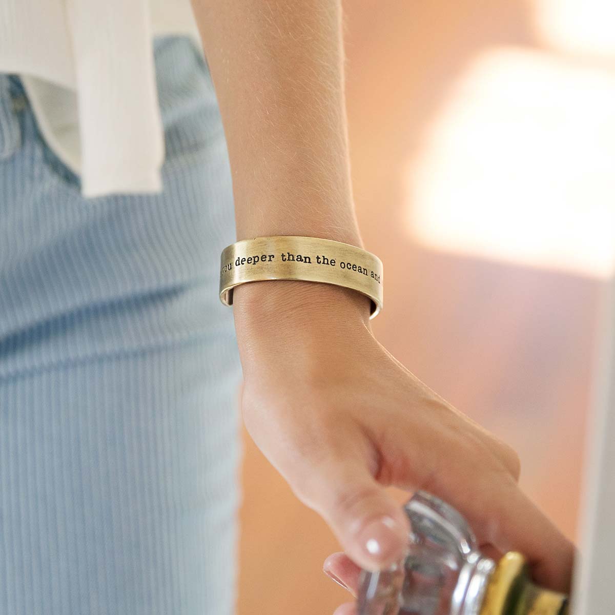 Girl wearing engraved artisan bronze-plated pewter deeper than the ocean cuff bracelet