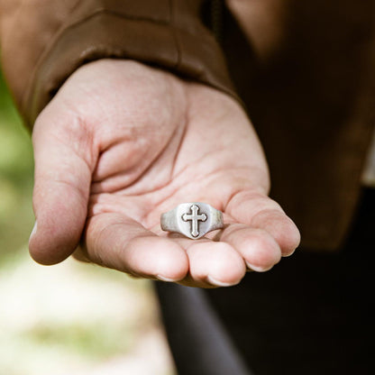 Man showing Faith Hope and Love Cross Signet ring handcrafted in sterling silver with an antiqued finish along with other sterling silver jewelry