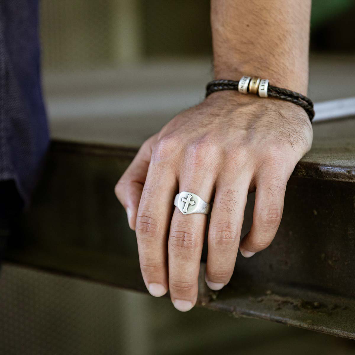 Man wearing Faith Hope and Love Cross Signet ring handcrafted in sterling silver with an antiqued finish along with other sterling silver jewelry