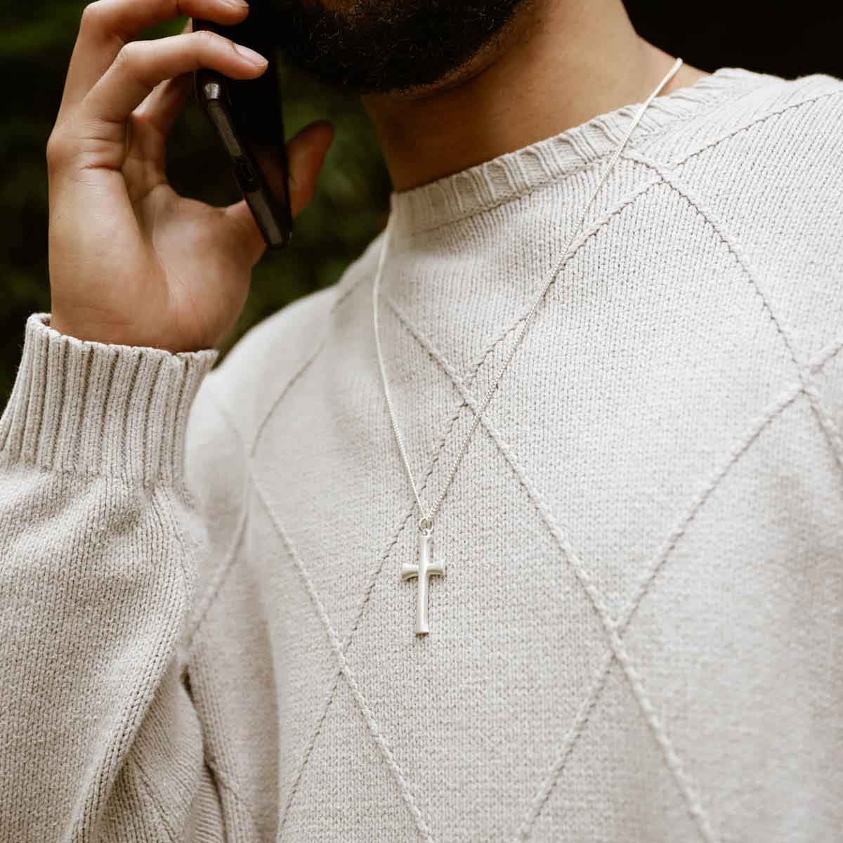 man holding a sterling silver Faith Through Love Cross Necklace