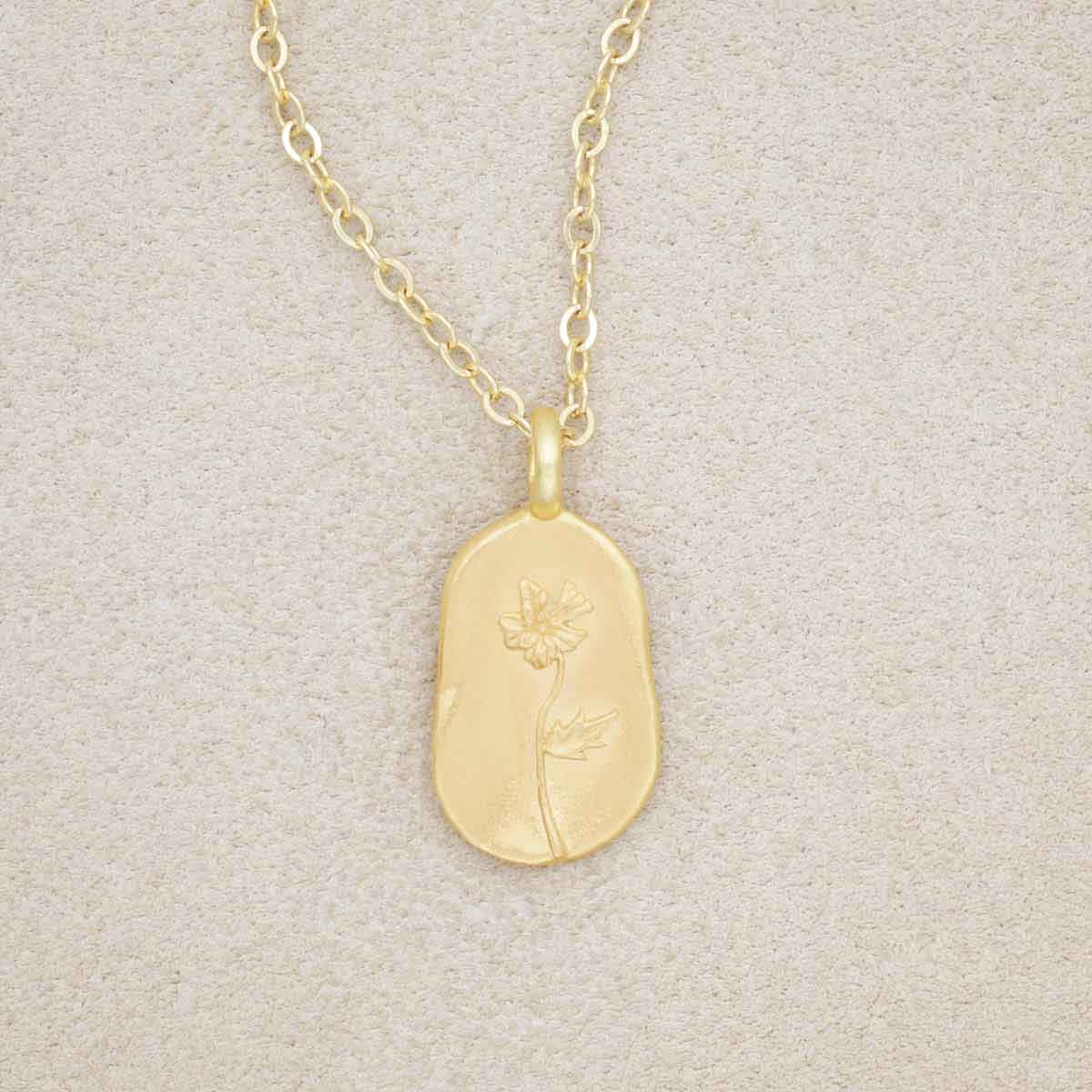 gold plated February birth flower necklace with an 18" gold filled link chain, on a beige background