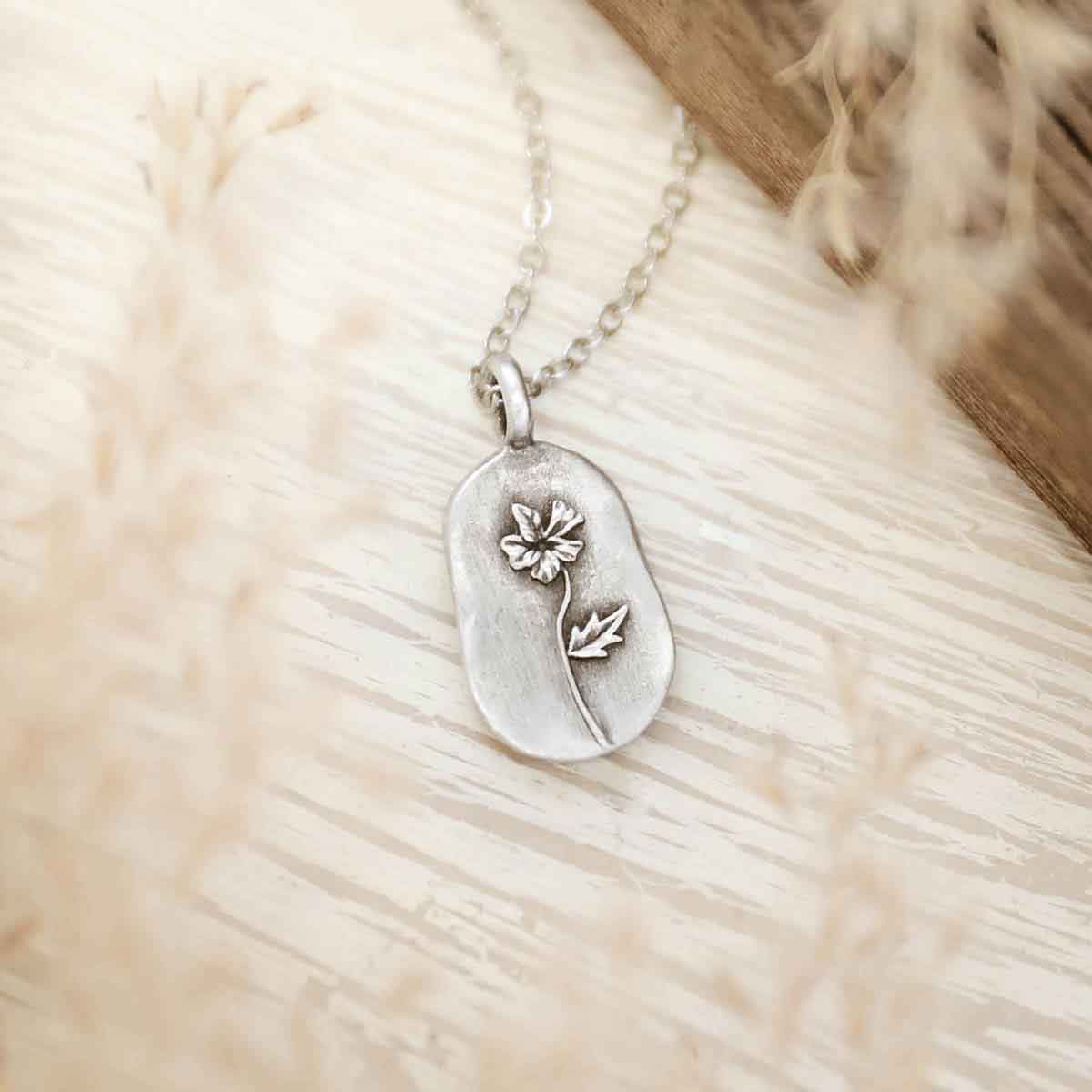 girl holding a pewter February Birth Flower necklace with an 18" link chain