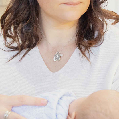 Girl wearing her February birth flower necklace handcrafted in sterling silver with a special birth month charm strung with a vintage freshwater pearl