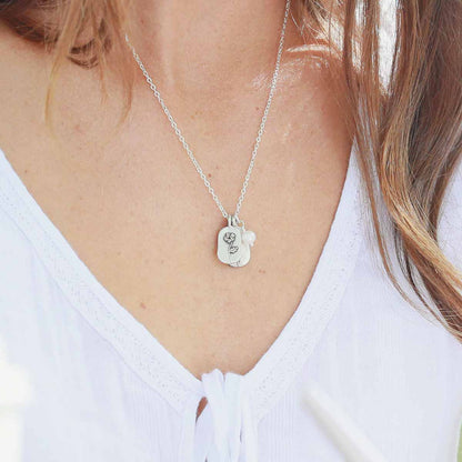 Girl wearing her February birth flower necklace handcrafted in sterling silver with a special birth month charm strung with a vintage freshwater pearl