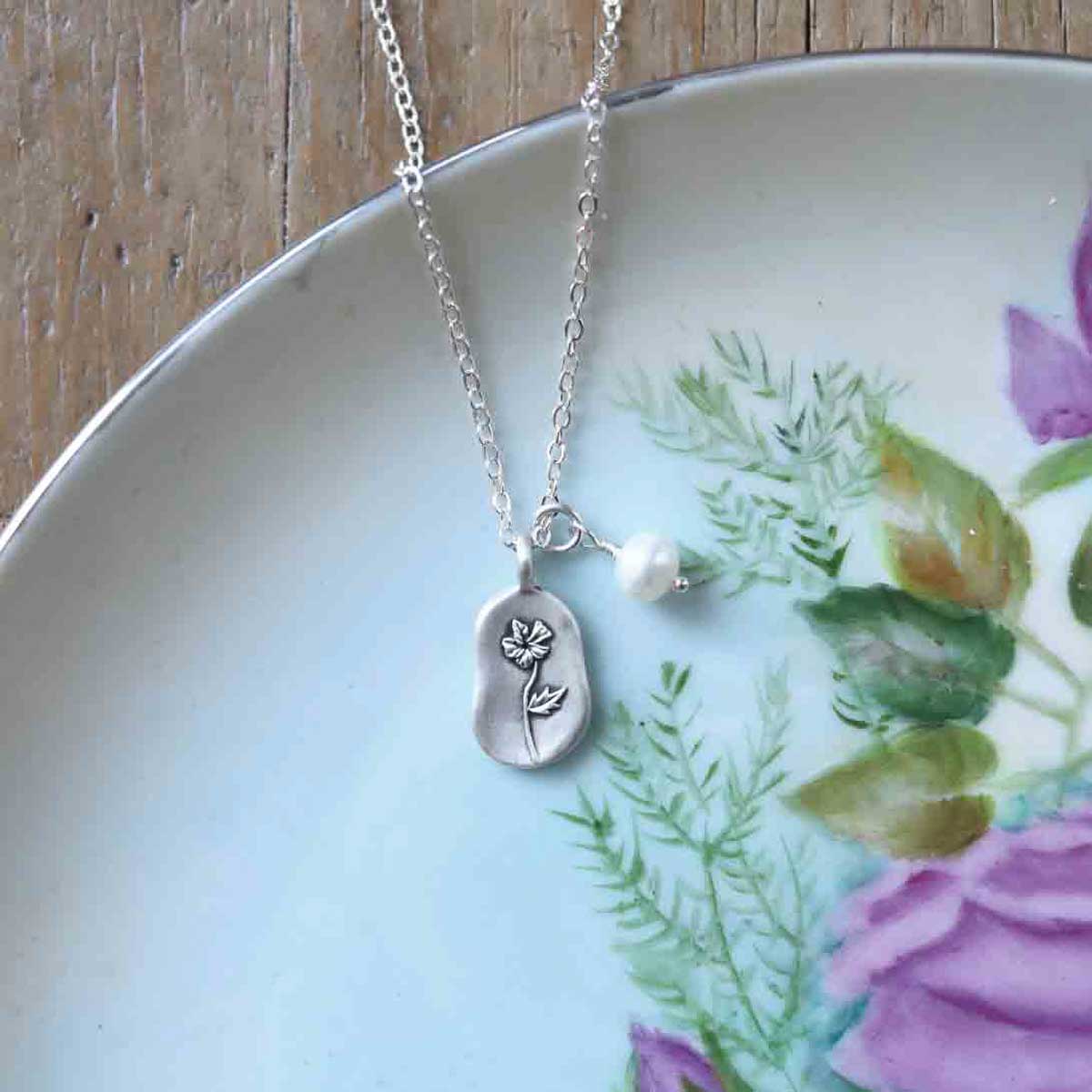 February birth flower necklace handcrafted in sterling silver with a special birth month charm strung with a vintage freshwater pearl