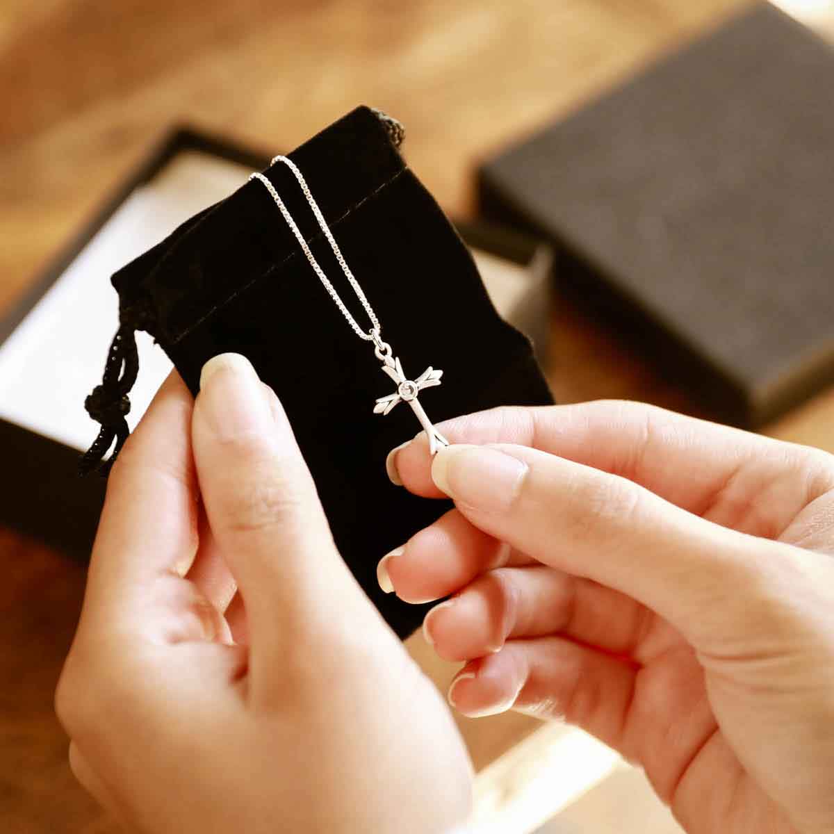 woman holding a sterling silver Firstfruits Cross Necklace