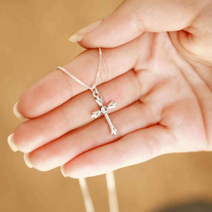 woman holding a sterling silver Firstfruits Cross Necklace