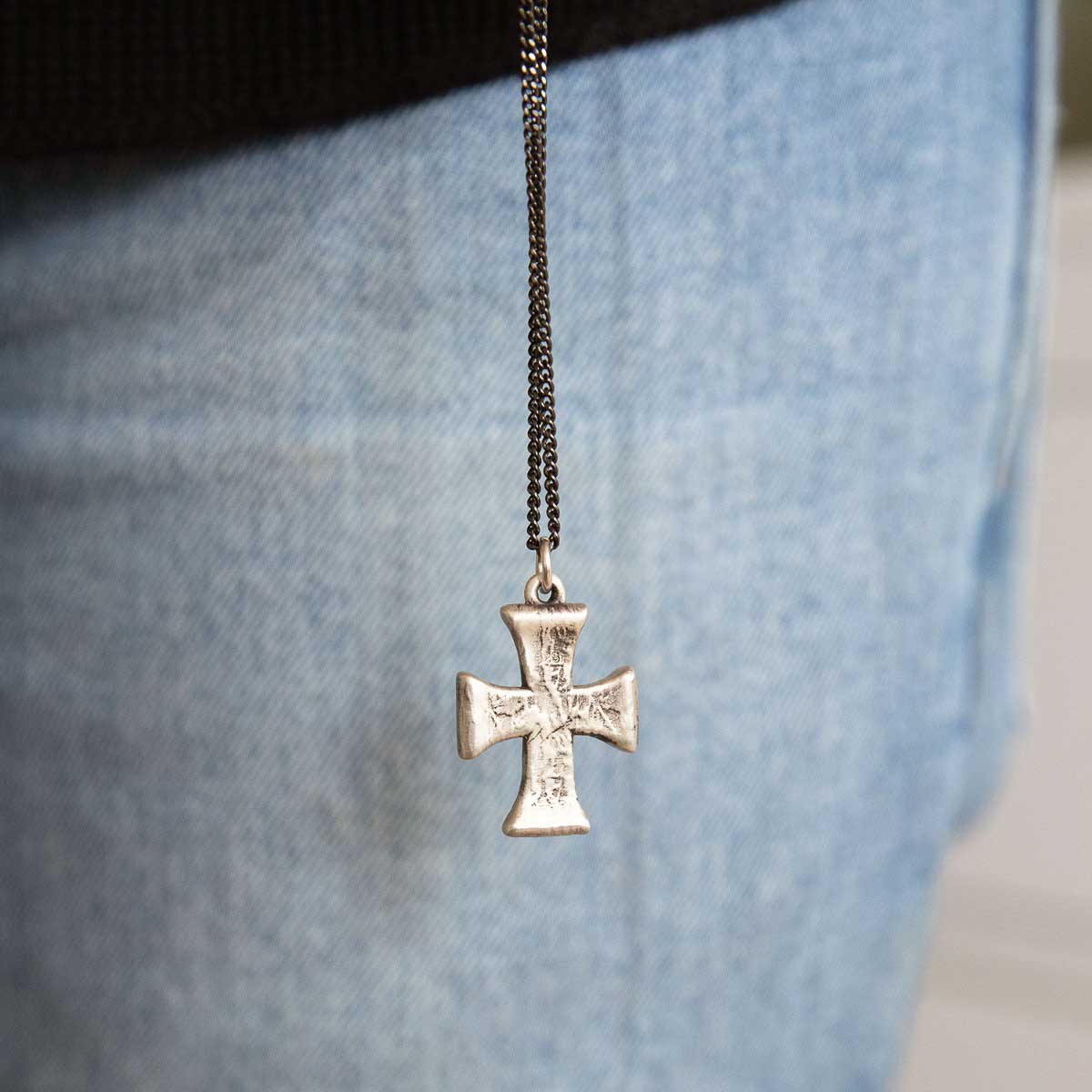 man holding a sterling silver Flourish Cross Necklace