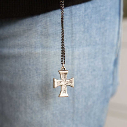 man holding a sterling silver Flourish Cross Necklace