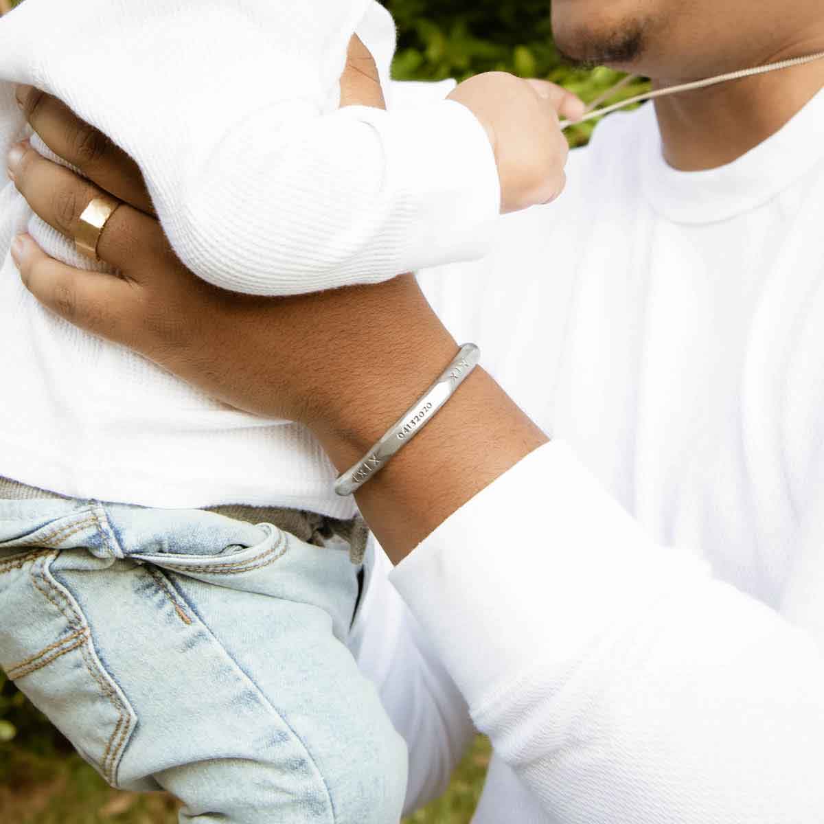 Man with his daughter while wearing Forge a path men's cuff bracelet hand-carved in fine pewter personalized with a name