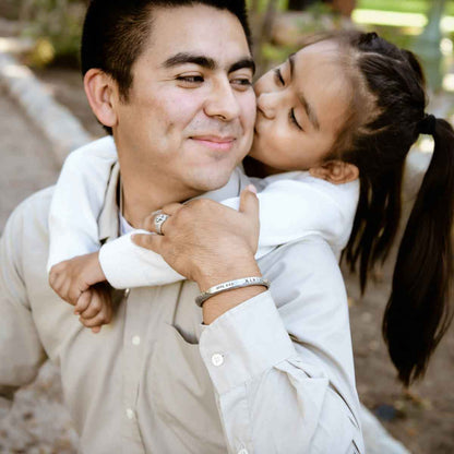 Man with his daughter while wearing Forge a path men's cuff bracelet hand-carved in fine pewter personalized with a name