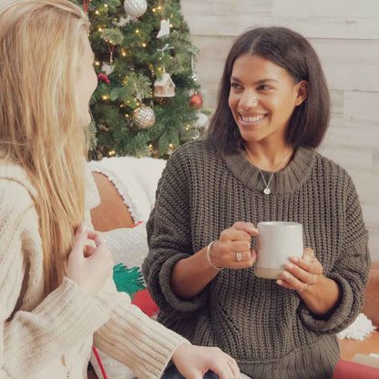 woman wearing a sterling silver full of love necklace with a friend in christmas living room