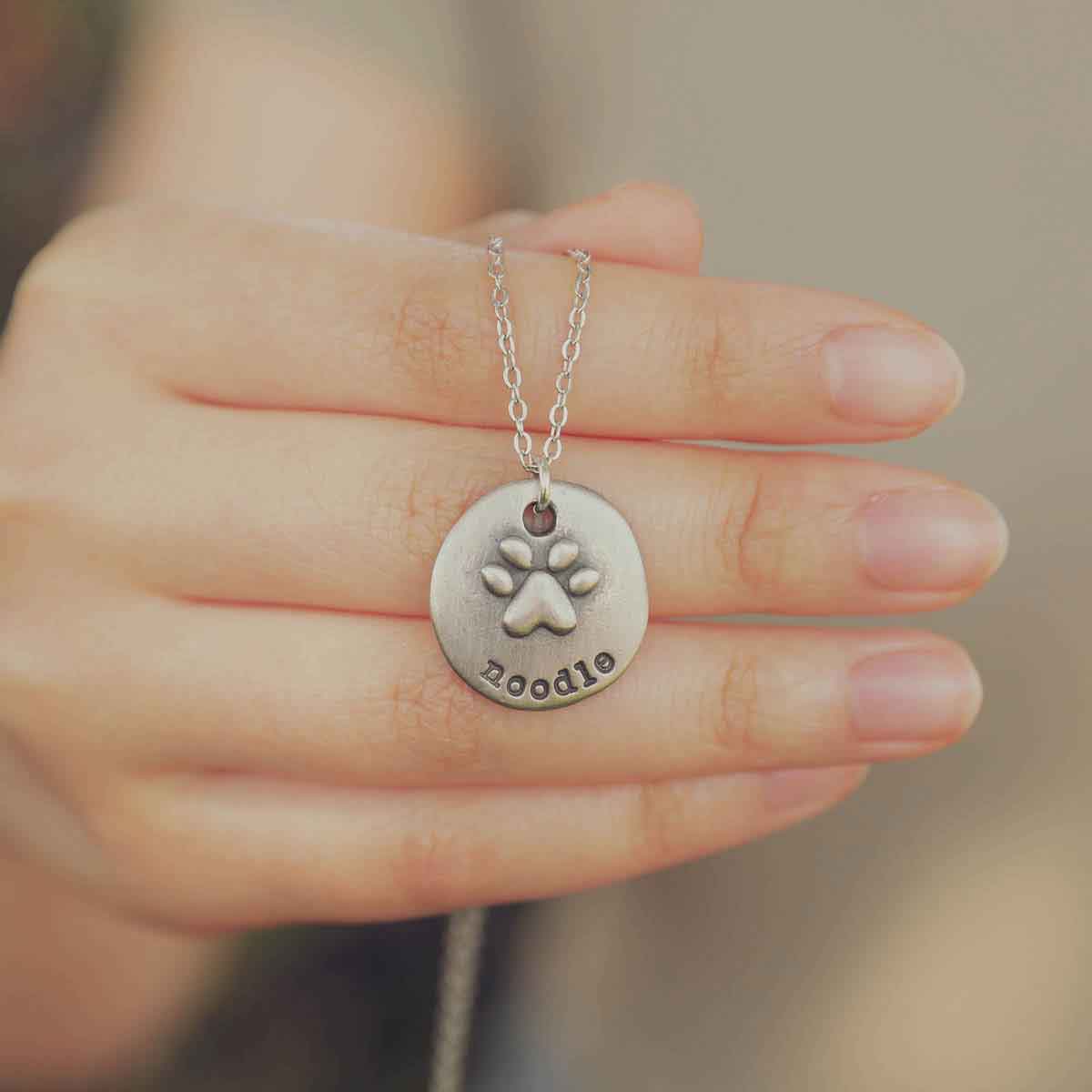 Girl wearing her Furry footprint necklace handcrafted in sterling silver with a paw engraved and personalized with a pet's name