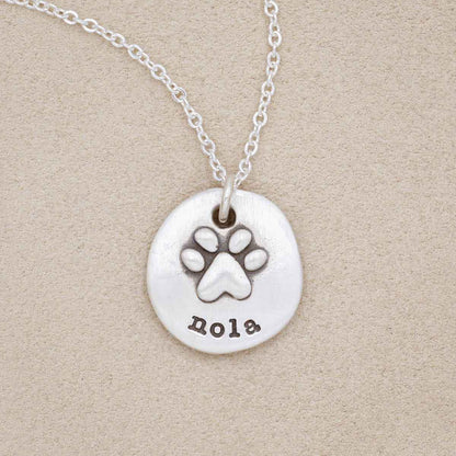 Furry footprint necklace handcrafted in sterling silver with a paw engraved and personalized with a pet's name