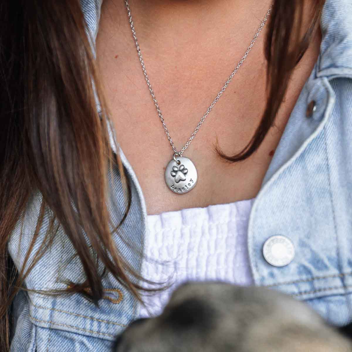 Girl and her dog wearing her Furry footprint necklace handcrafted in sterling silver with a paw engraved and personalized with a pet's name