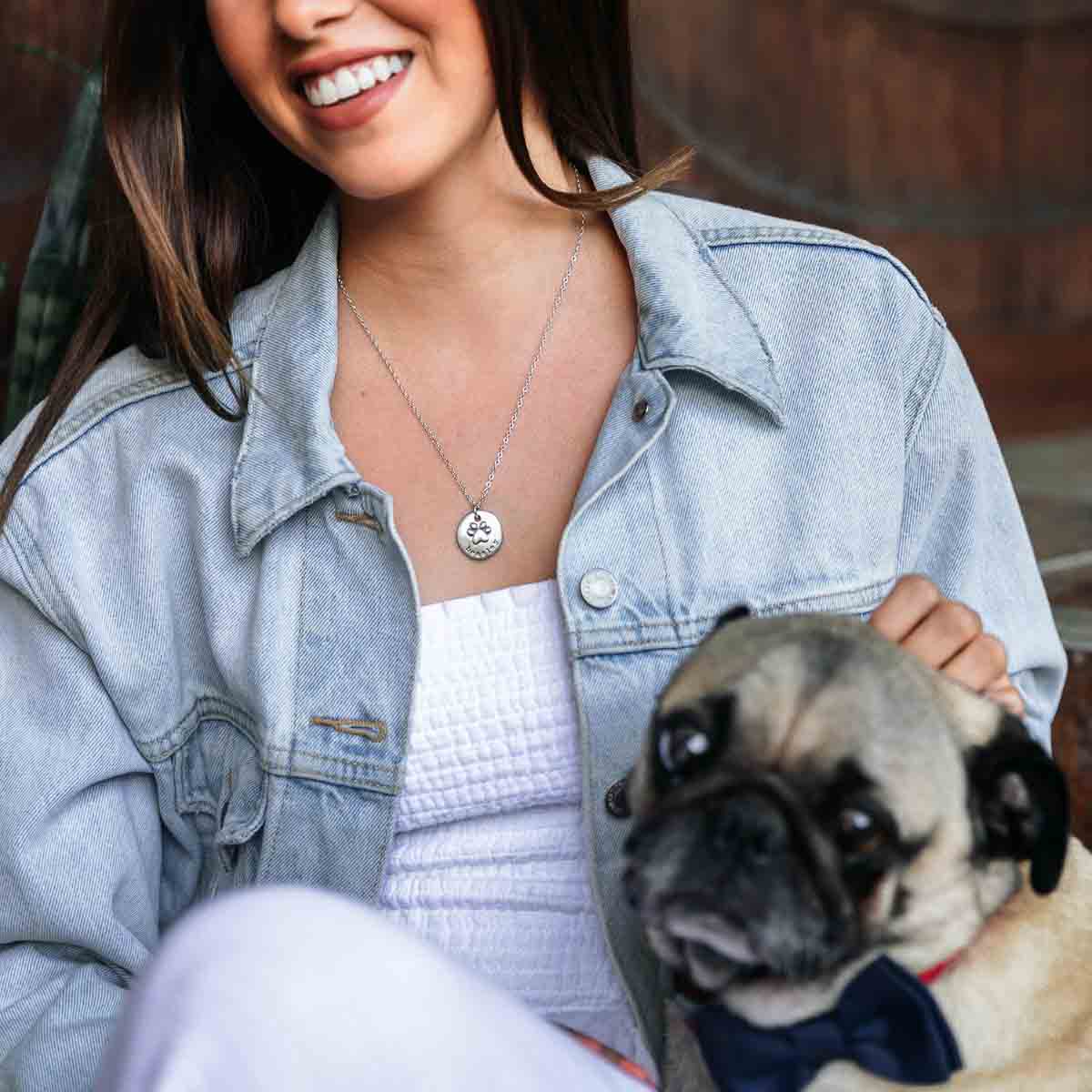 Girl wearing her Furry footprint necklace handcrafted in sterling silver with a paw engraved and personalized with a pet's name