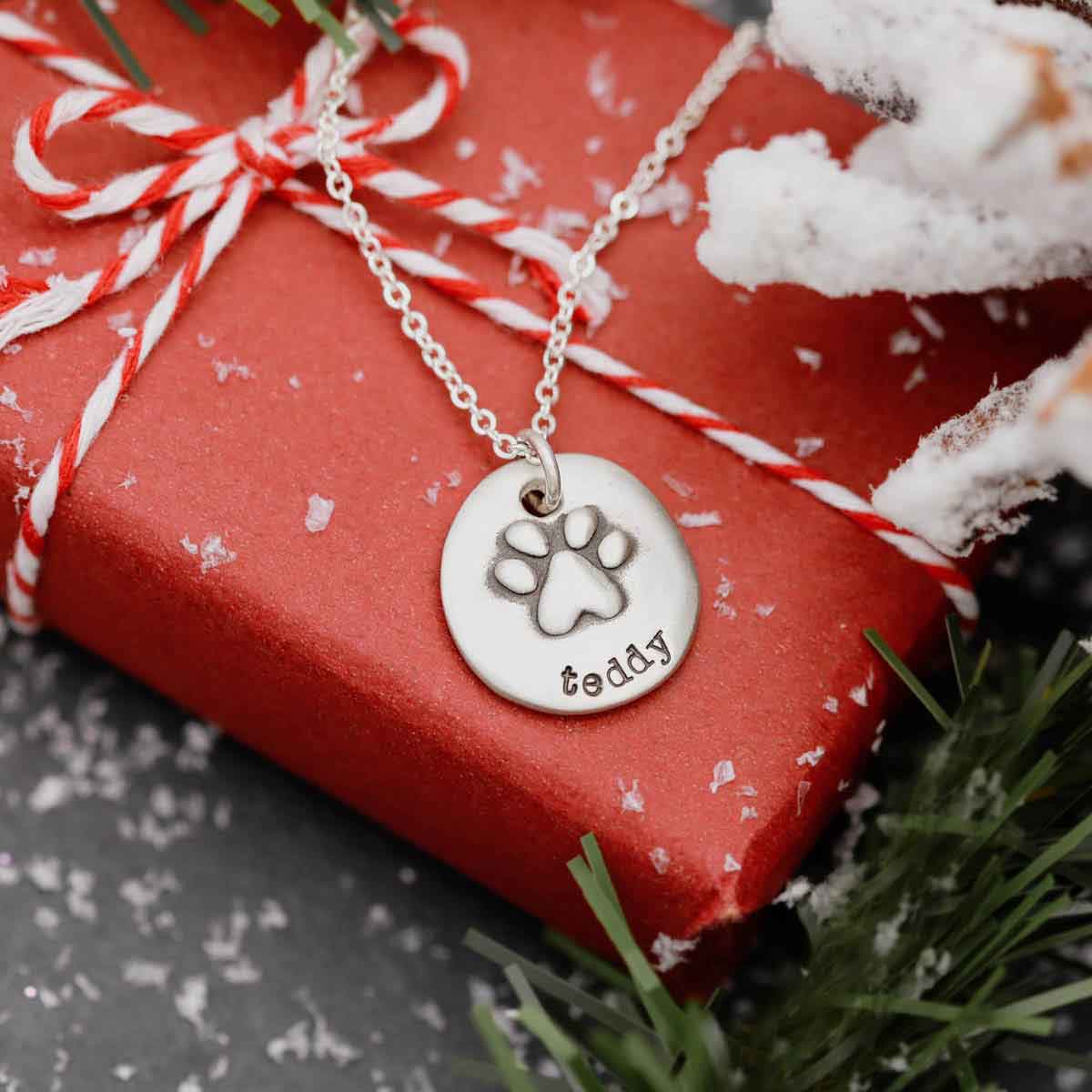 Furry footprint necklace handcrafted in sterling silver with a paw engraved and personalized with a pet's name