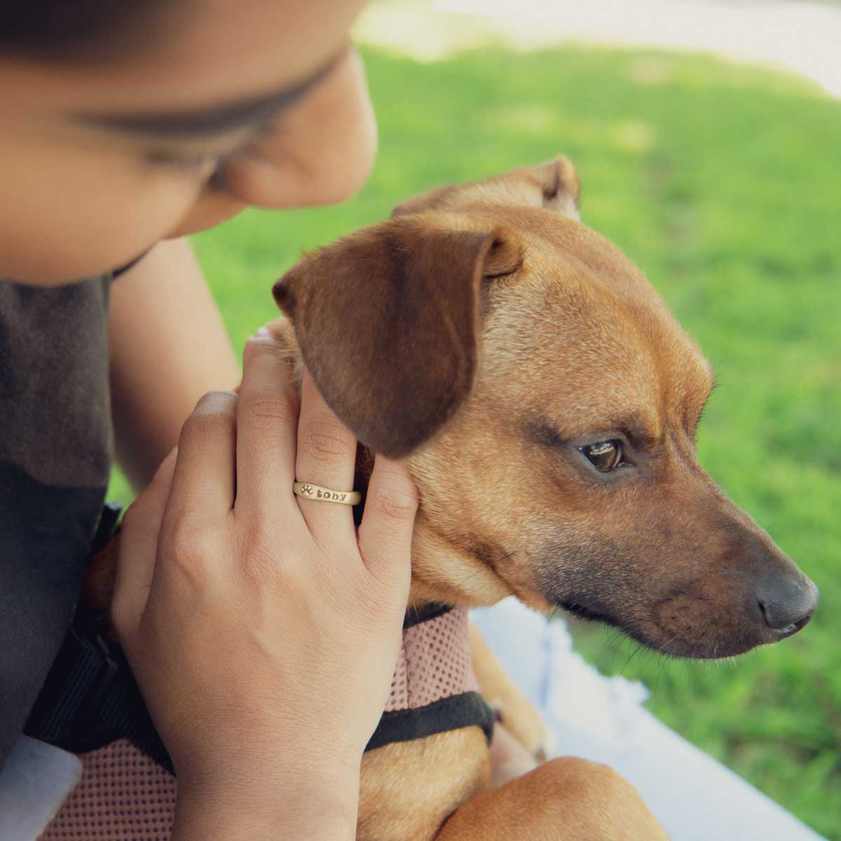 woman wearing her furry footprint 14k yellow gold stacking rings personalized with pet names next to her puppy