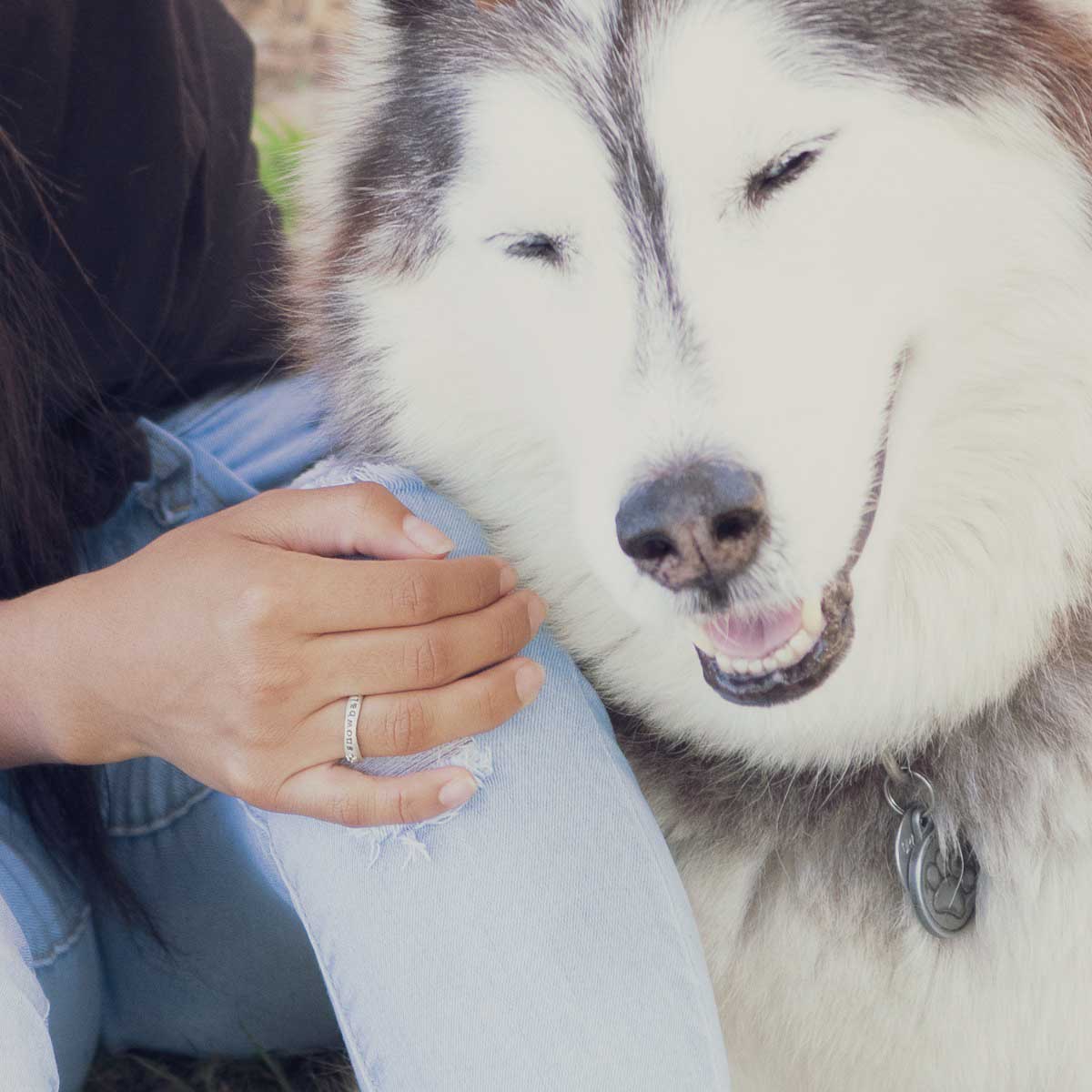 Woman wearing her furry footprint sterling silver stacking ring personalized next to her dog