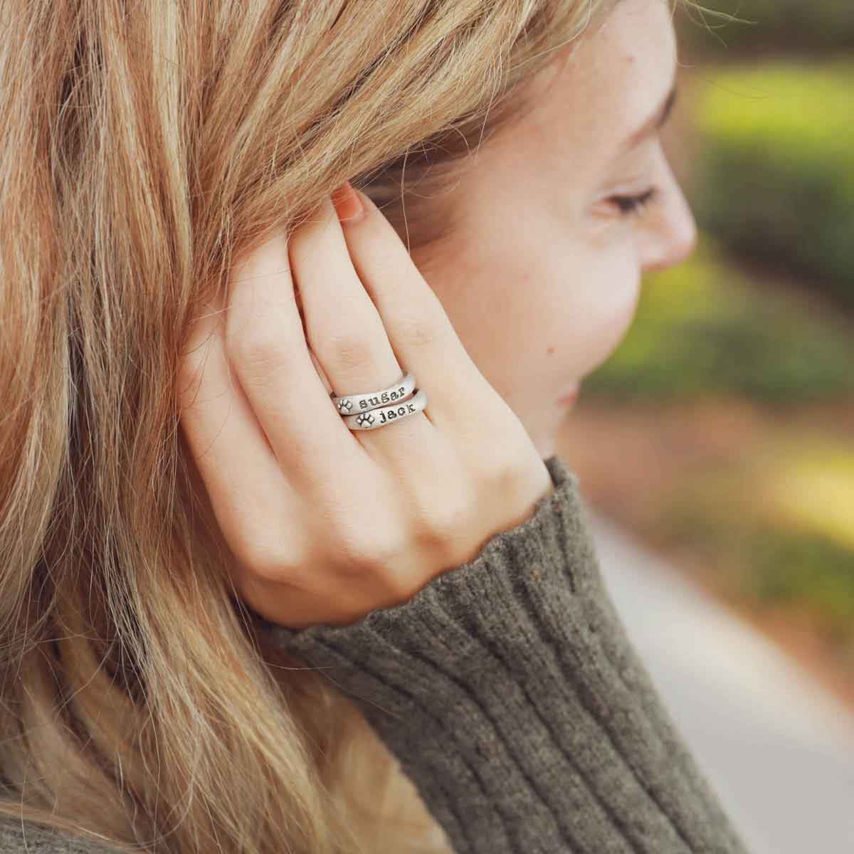 Woman wearing her furry footprint sterling silver stacking rings personalized with her pet names