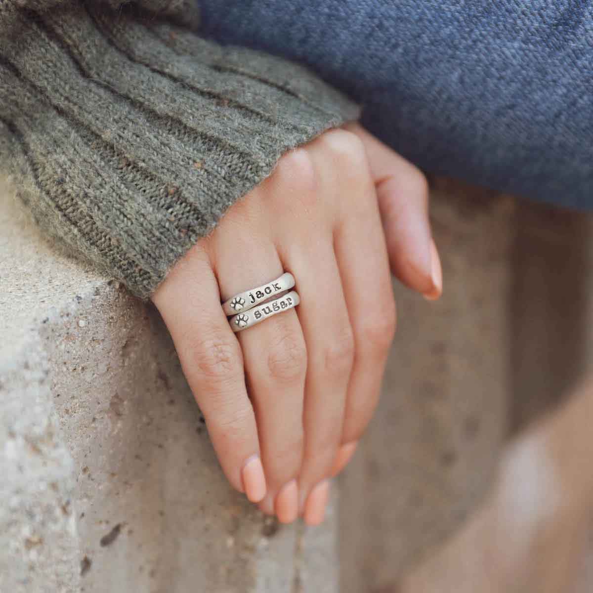 Woman wearing her furry footprint sterling silver stacking rings personalized with her pet names